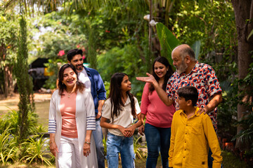 Indian family enjoying fun talk and laughter while walking together on lawn outdoors