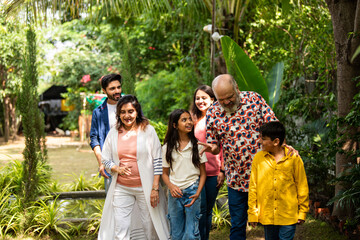 Indian family enjoying fun talk and laughter while walking together on lawn outdoors