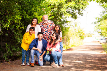 Indian family bonding happily while standing outdoors and smiling together