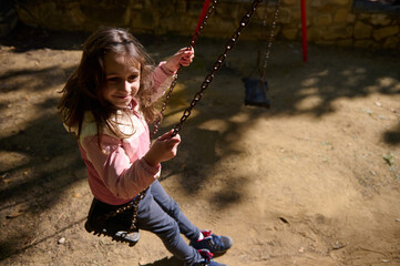 Sunny Day Swing: Happy Girl On a Park Swing Laughing Outdoors