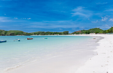 Lombok Indonesia  – White sand, turquoise waters and boats resting on the calm shore of Tanjung Aan Beach, a true tropical paradise.