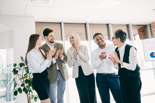 Business professionals gathered in casual discussion and celebrating teamwork success in a collaborative office environment