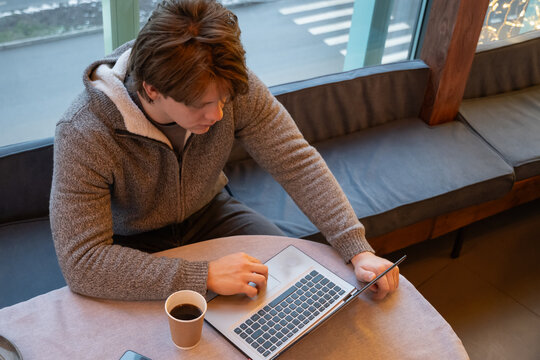 Young man working with laptop in coffee shop. Coffee Break at Cafe