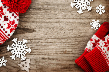 Christmas winter red hat and mittens, wooden snowflake decorations ornaments on old wooden greeting board background. Merry Christmas design element.