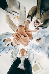 Business professionals join hands in a gesture of teamwork and unity, showcasing collaborative...