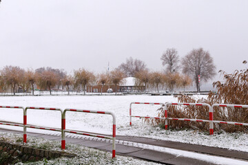 Winter field with red fence. Snow covered field with red metal fence and distant trees. Concept of contrast landscape, winter background, and outdoor minimal design.