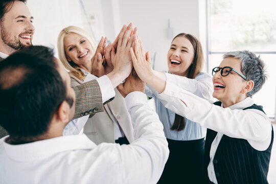 Group of colleagues achieving a high-five in an office setting showcasing teamwork, collaboration, and motivation