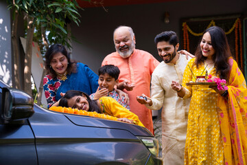 Indian family performing car puja ceremony to welcome their new vehicle with blessings