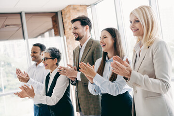 Diverse business team smiling and applauding in a modern office during a corporate meeting