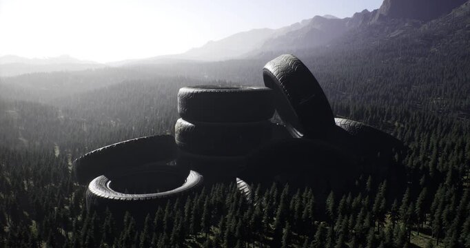 A massive stack of old tires rests in a dense forest surrounded by mountains. The sun casts shadows over the landscape, highlighting the contrast of the rubber and greenery.
