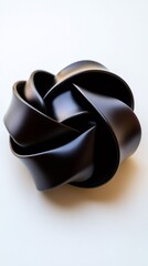 Abstract black knot sculpture forming complex interwoven pattern