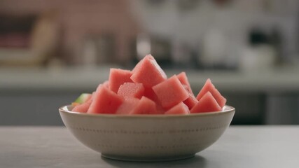 A fresh and vibrant bowl filled with cut watermelon chunks. The scene conveys freshness and summer delight