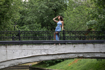 Naklejka premium Young beautiful brunette woman in blue knitted dress posing in summer park
