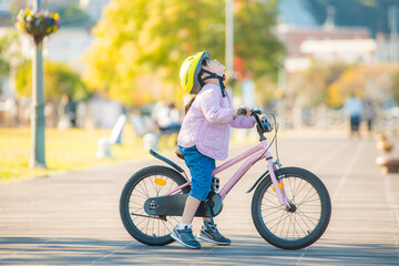 Obraz premium 自転車にまたがり空を見上げる女の子と明るい公園の屋外風景