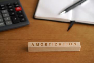 Fototapeta premium AMORTIZATION. Financial concepts. Wooden letters with calculator and notebook in the background.