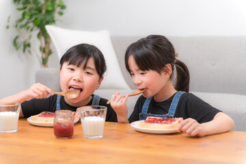 食パンにジャムをのせて食べる子どもたちの家庭的な朝の時間