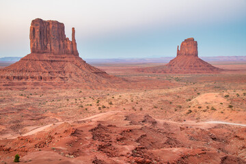 Vast desert landscape of Monument Valley bathed in warm sunlight with dramatic sandstone mesas