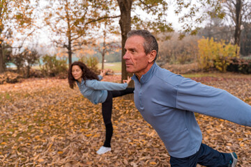 Senior man and woman focus on balance during morning exercise in park
