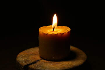 Closeup beautiful burning nature bees wax candle fire on dark black background in the center, candle fire flame light with empty copy space. Ritual with romantic home decor candle fire with no people