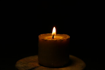 Closeup beautiful burning nature bees wax candle fire on dark black background in the center, candle fire flame light with empty copy space. Ritual with romantic home decor candle fire with no people