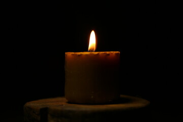 Closeup beautiful burning nature bees wax candle fire on dark black background in the center, candle fire flame light with empty copy space. Ritual with romantic home decor candle fire with no people