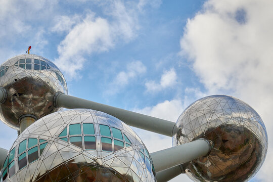 Wide-angle view of the Atomium monument in Brussels under daylight. The symmetrical spheres and connecting tubes stand tall against a partly cloudy sky.