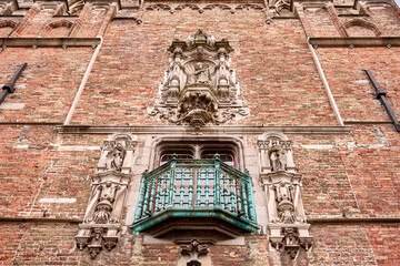 Close-up of a decorative green balcony and stone statues on the facade of the Belfry of Bruges. A fine example of Gothic craftsmanship and medieval architecture in Belgium.