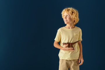 Blonde boy with wavy hair enjoys playful moments in studio setting on blue backdrop