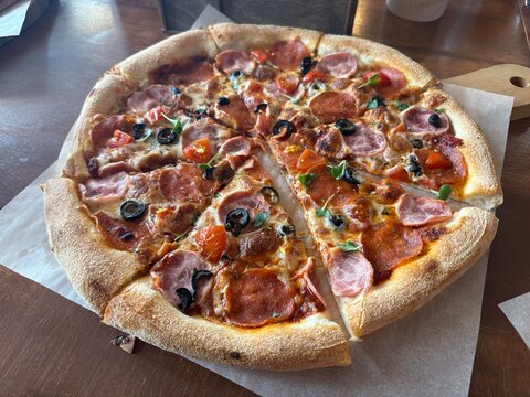 Pizza slices on wooden table with toppings of ham and olives   - Powered by Adobe
