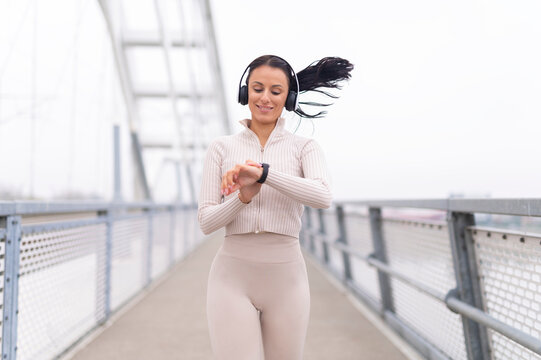 Woman running and checking smartwatch on bridge