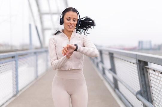 Woman checking fitness data on smartwatch while running - Powered by Adobe