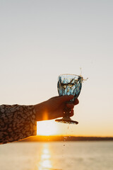 Wine Glass in Hand Against Sunset Sky and Sea &ndash; Toasting to Beauty and Freedom
