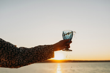 Wine Glass in Hand Against Sunset Sky and Sea &ndash; Toasting to Beauty and Freedom