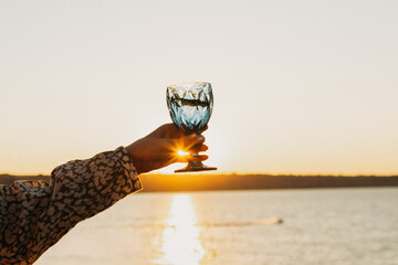 Wine Glass in Hand Against Sunset Sky and Sea – Toasting to Beauty and Freedom