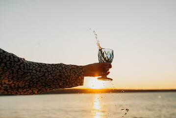 Wine Glass in Hand Against Sunset Sky and Sea – Toasting to Beauty and Freedom