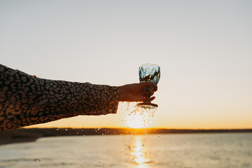 Wine Glass in Hand Against Sunset Sky and Sea &ndash; Toasting to Beauty and Freedom