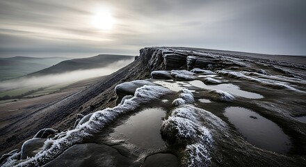 A scenic panoramic vista from a craggy, elevated plateau on an overcast day with the sun partially obscured