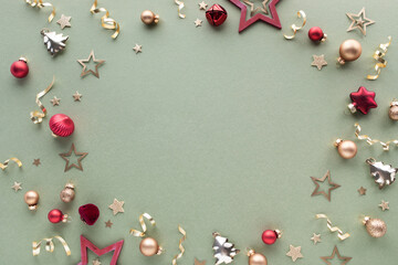 Obraz premium Festive Christmas composition with shiny golden and red baubles and stars on green background top view, flat lay.