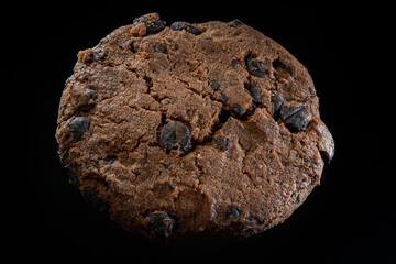 Close-up macro of a chocolate cookie on a black background. Crisp texture and rich tones make it perfect for bakery, dessert and food design.