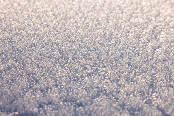 macro of frosty snow crystals receding into a bright soft glow, abstract winter texture background with depth and copy space for seasonal designs.