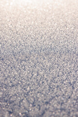 Sparkling layer of fresh snow crystals in soft sunrise light, detailed macro texture background for winter, Christmas or seasonal design projects.