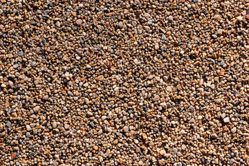 Warm-toned small pebbles forming a natural gravel texture, full frame top view, ideal seamless background for construction, landscaping, nature or beach themed designs.Warm-toned small pebbles forming