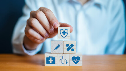 Hand placing a block with a medical shield icon on a stack of blocks representing health insurance and healthcare