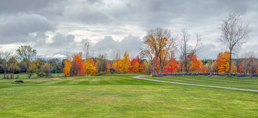 A beautiful golf course with coloured fall foliage on a cloudy autumn day in Canada