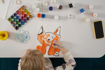 Child painting orange fox with watercolors, creative activity.