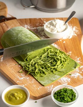 Corte de fideos verdes hechos a mano desde una masa de eneldo en una cocina moderna