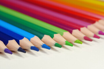 New wooden colored pencils of rainbow colors, perfectly sharpened, lie on table