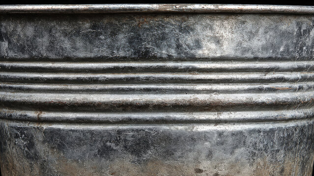 Close-up of a weathered, textured metal surface with horizontal ridges, showcasing a rustic, aged, and industrial aesthetic in shades of grey.