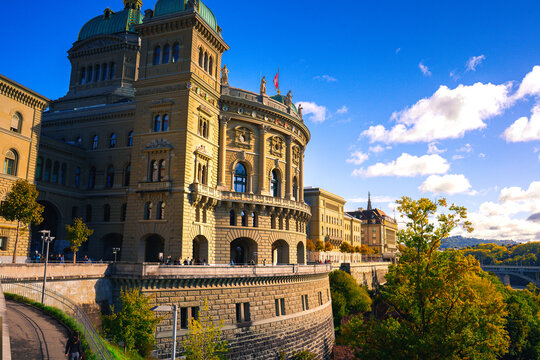 Majestic European government building on a sunny day in Bern, Switzerland. The bright colors highlight the historic architecture set against the vibrant autumnal greenery.