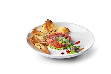 Tuna tartare served with avocado, microgreens, chili, and sesame chips on a white plate